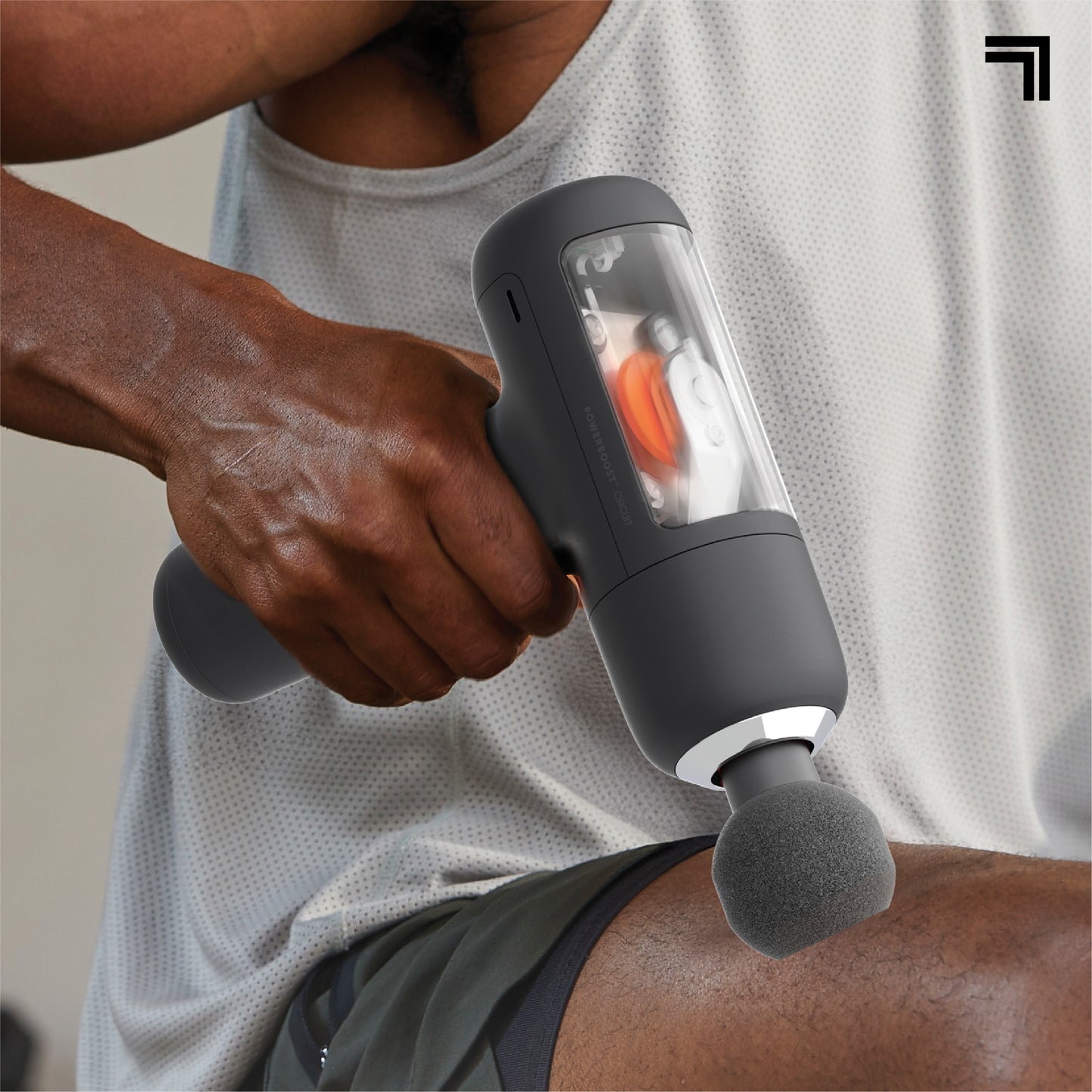 Person using the Sharper Image PowerBoost Circuit percussion massage gun with round attachment on a thigh muscle.